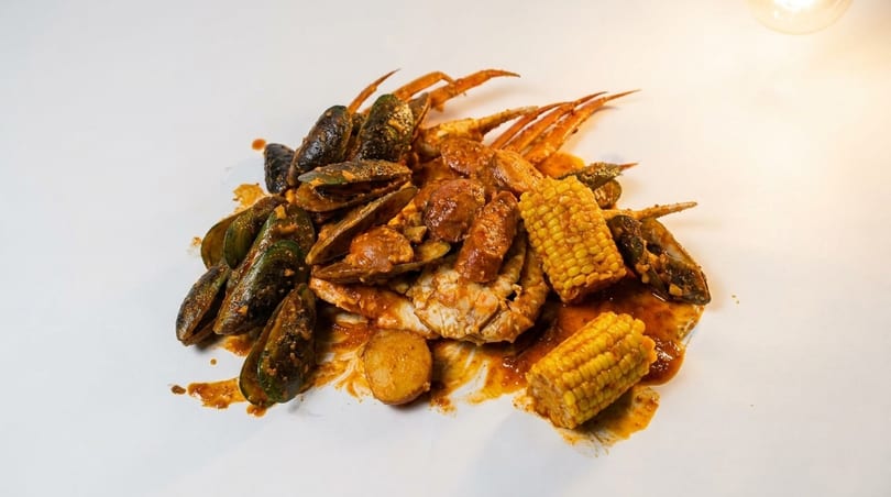 Seafood boil with mussels, crab, corn on the cob, and sausage in a rich sauce.